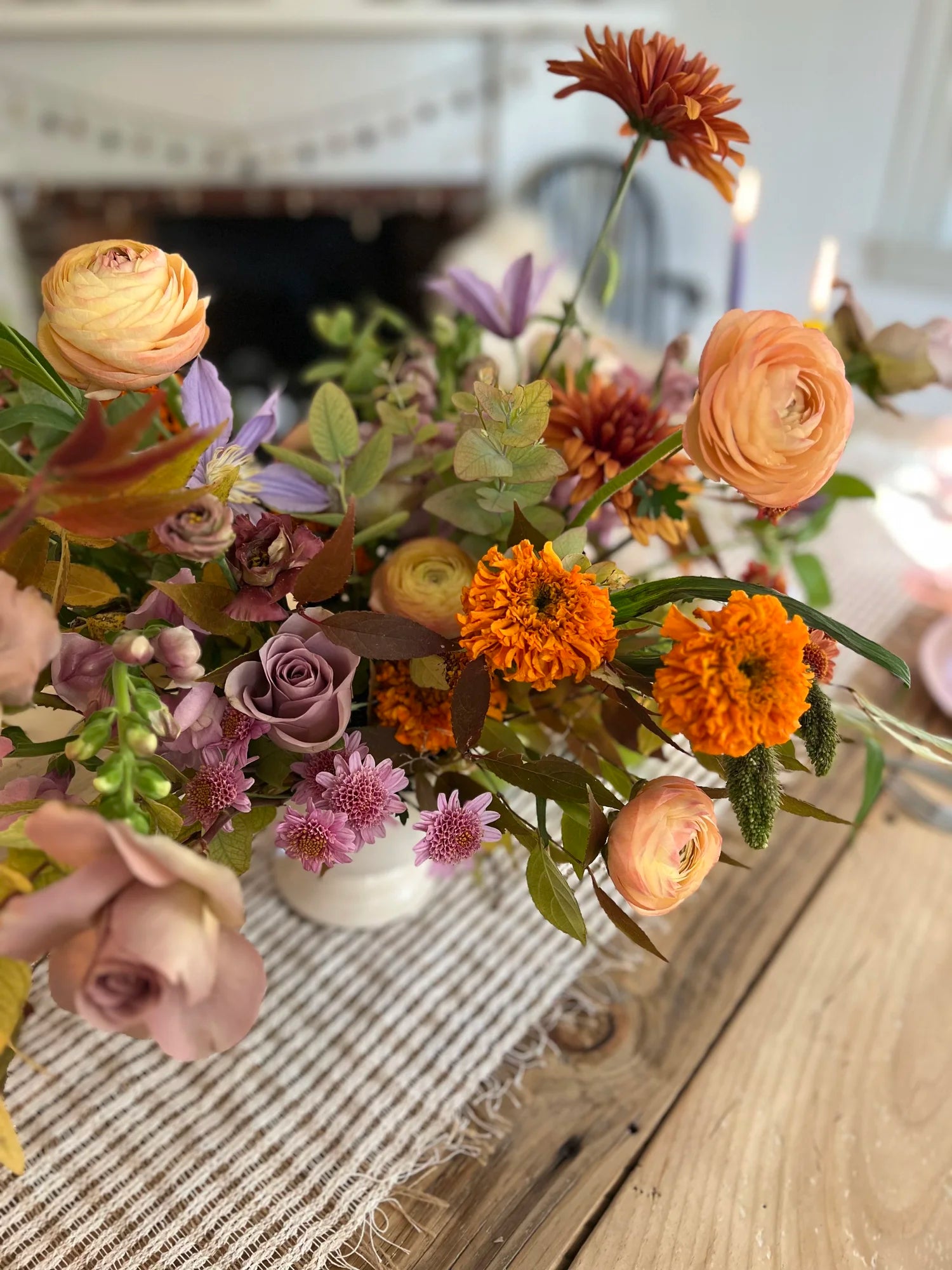 Colorful floral arrangement on a wooden table with a fireplace in the background