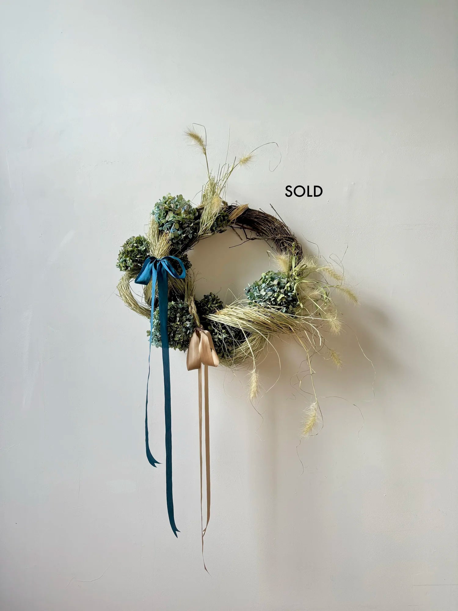 Decorative wreath with greenery and ribbons on a white background