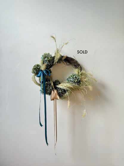 Decorative wreath with greenery and ribbons on a white background