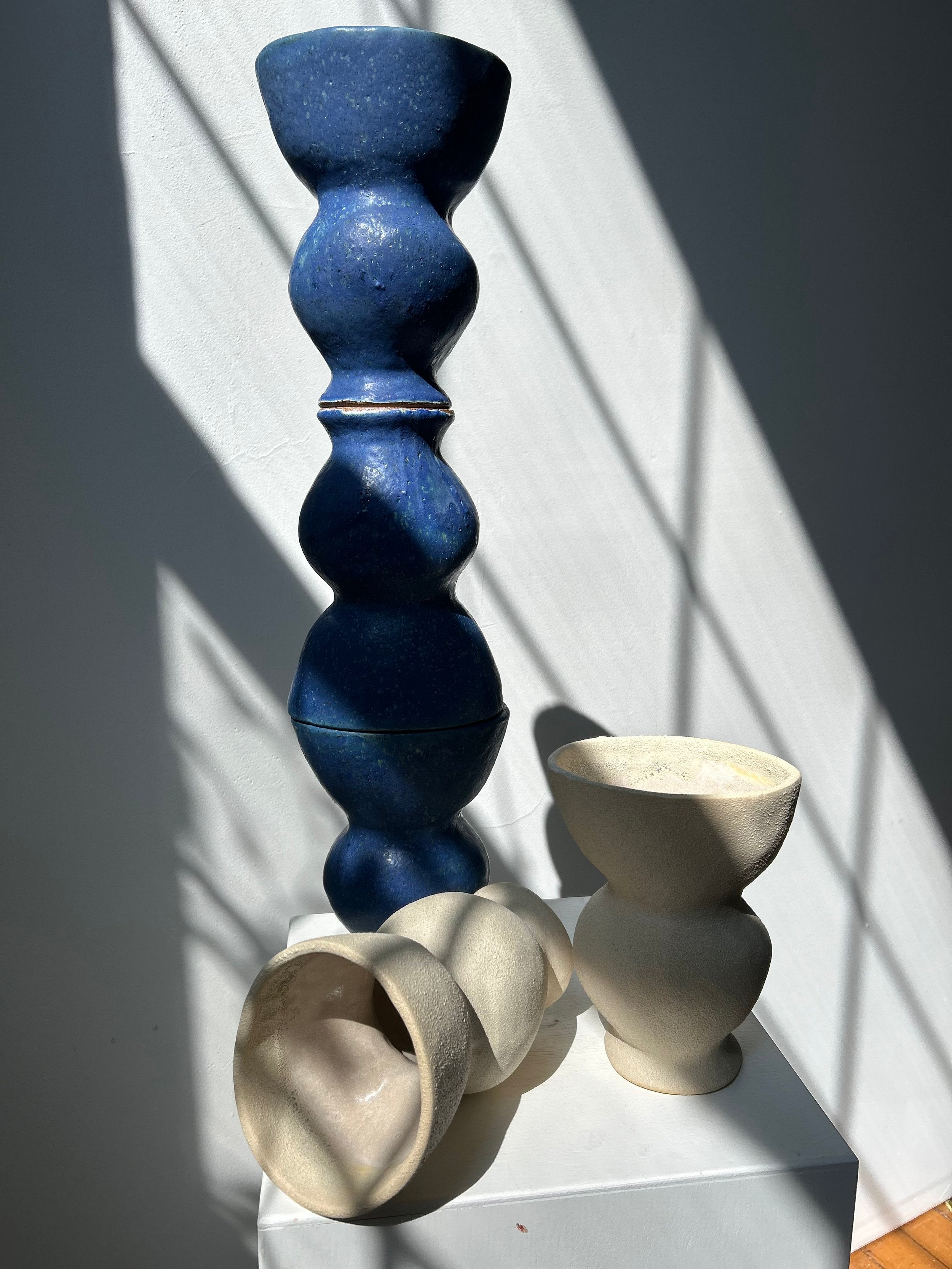 Three ceramic vases of different sizes on a white surface with a gray background