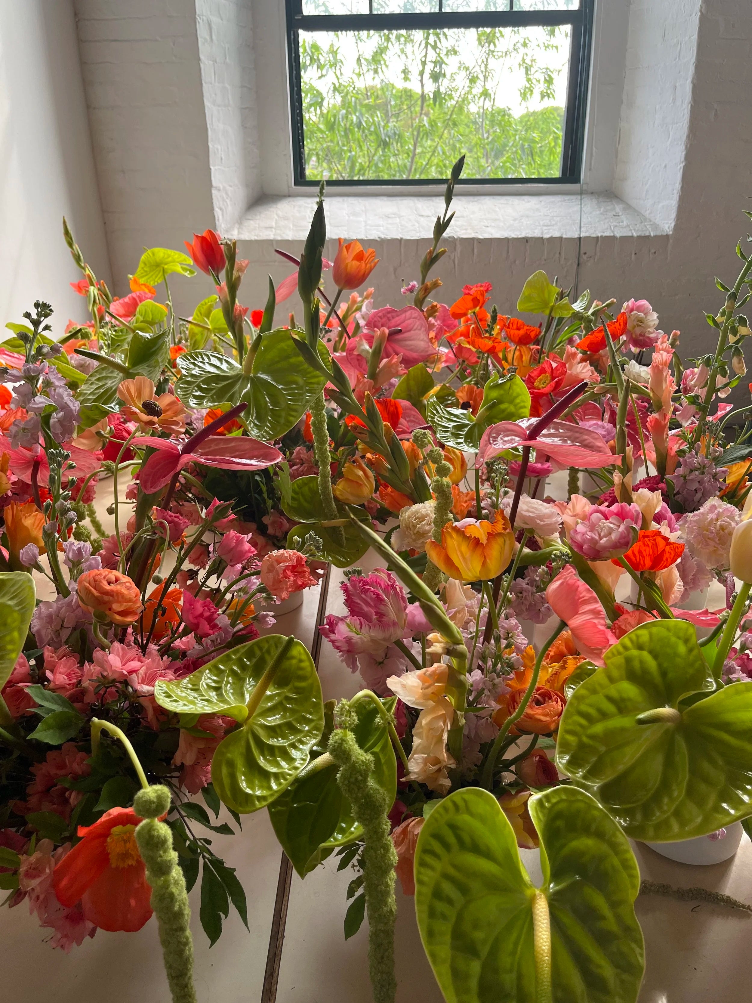 Colorful bouquet of flowers in a pot on a windowsill with greenery.