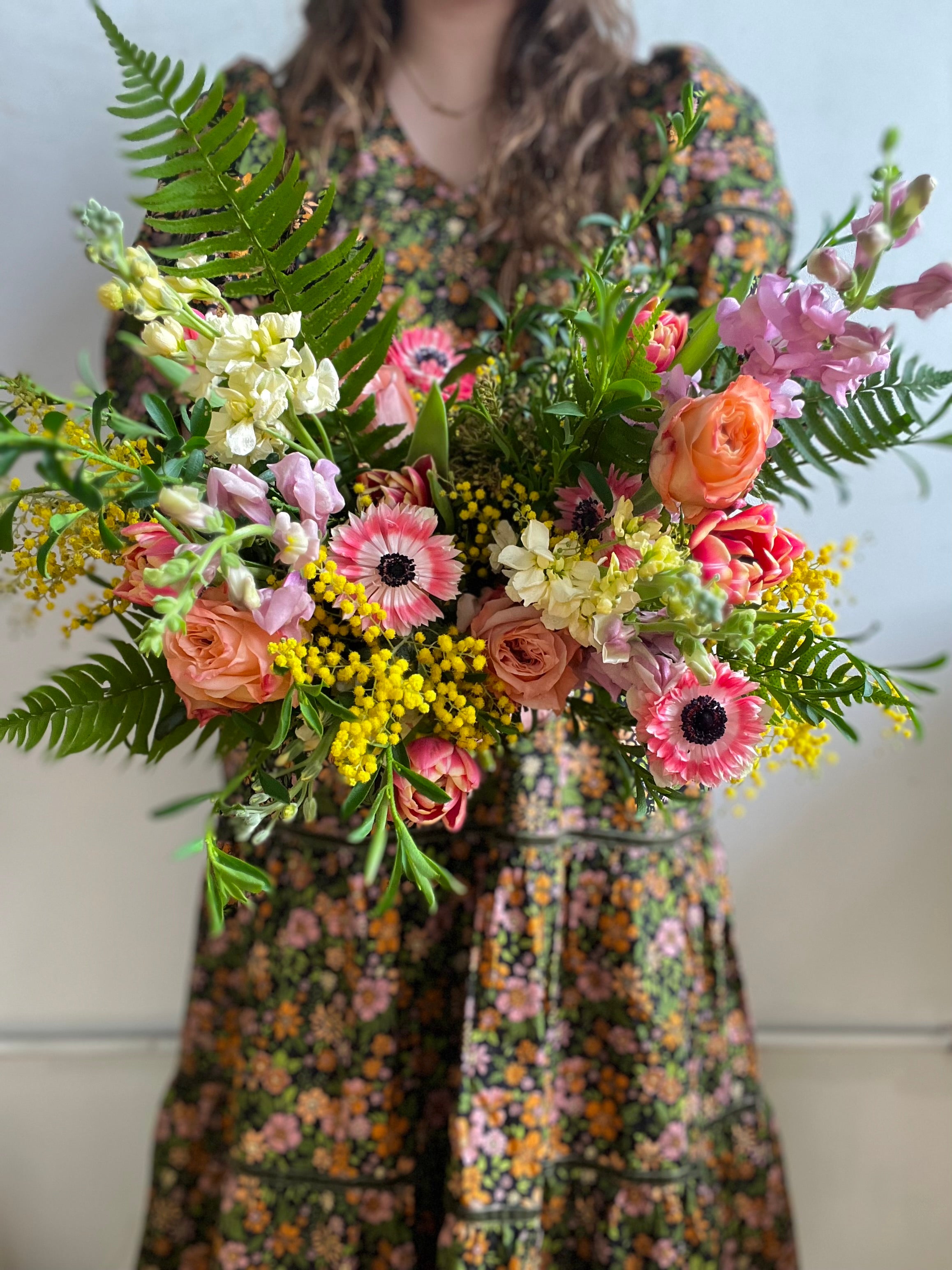 Bridesmaid holding a large colorful wedding party bouquet of flowers with a floral dress.