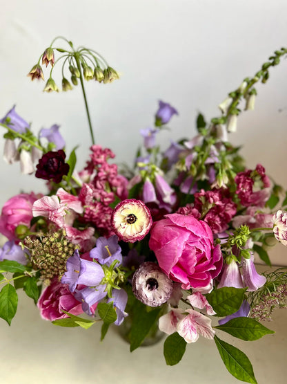 Colorful flower arrangement with pink, purple, and green flowers on a light background