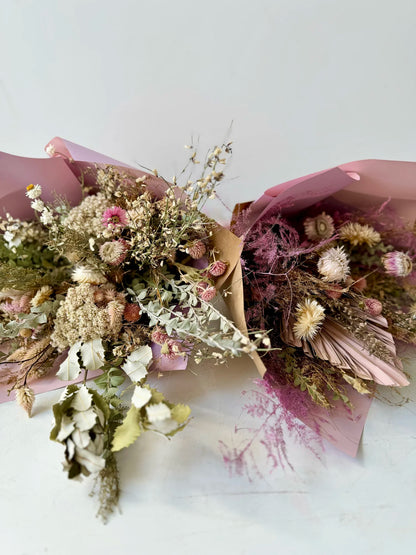 Bouquets of dried flowers in pink paper packaging on a white background