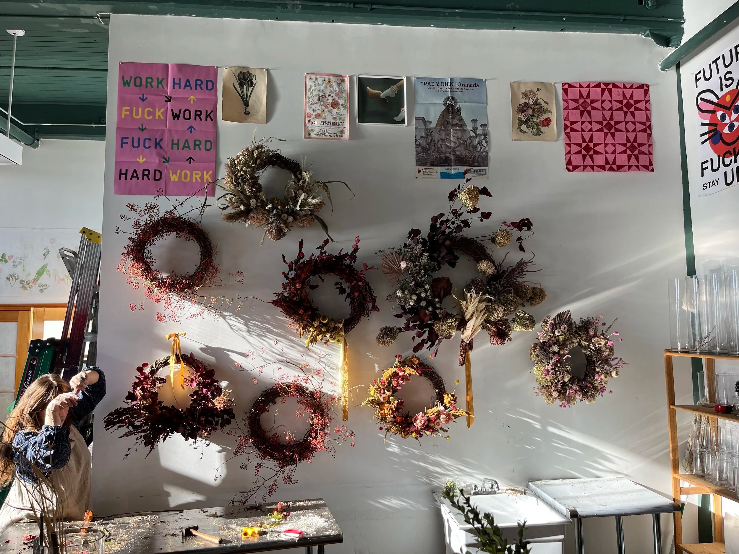 Wall with wreaths, artwork, and motivational posters in a room setting.