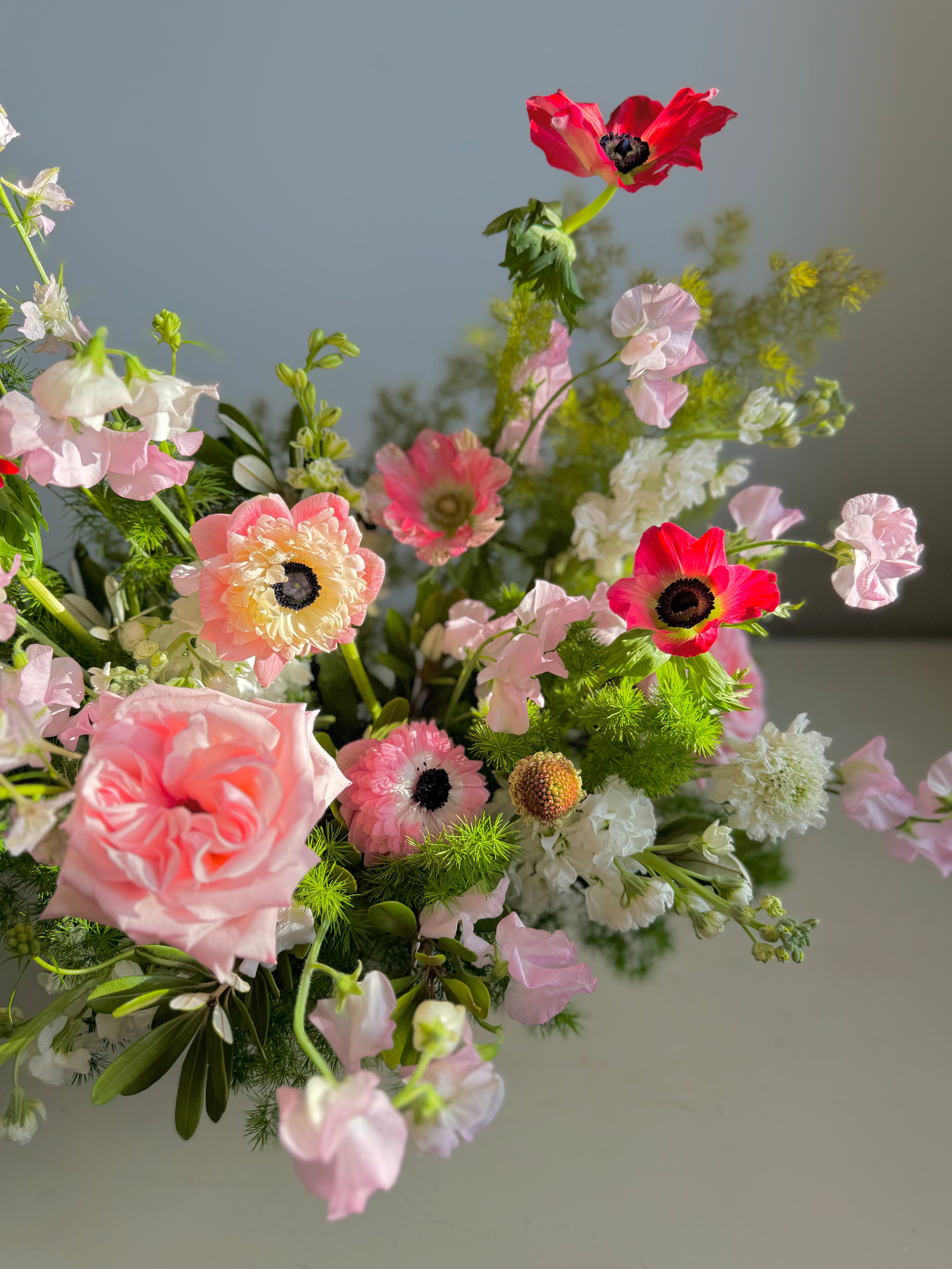 Bouquet of pink and white flowers with green leaves on a neutral background