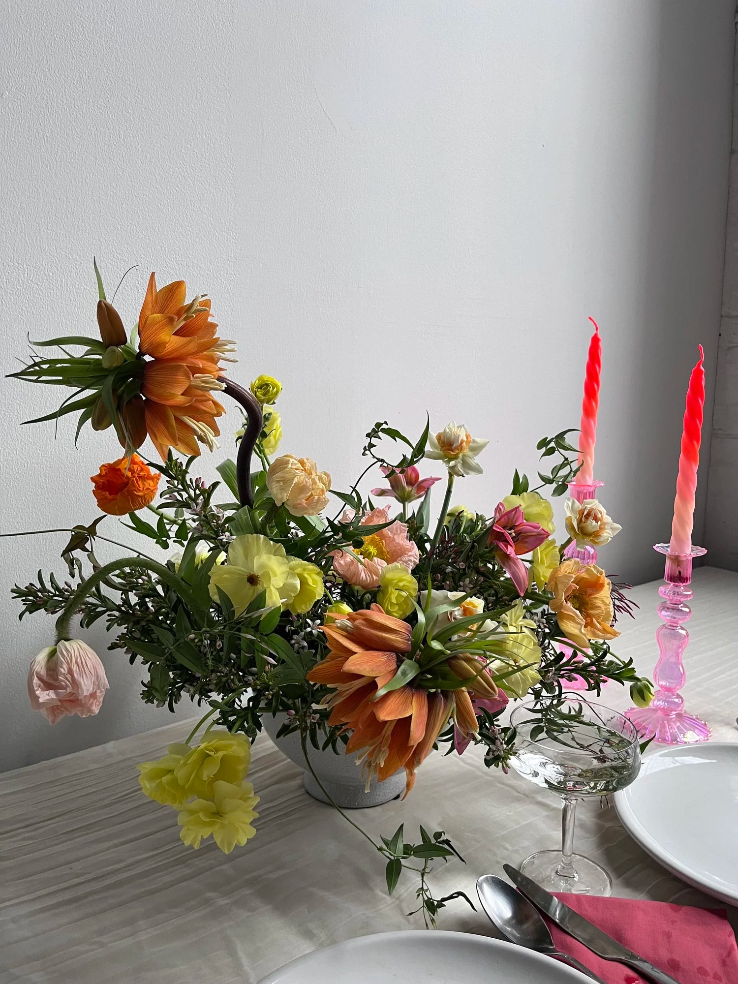 Floral arrangement on a table with candles and cutlery