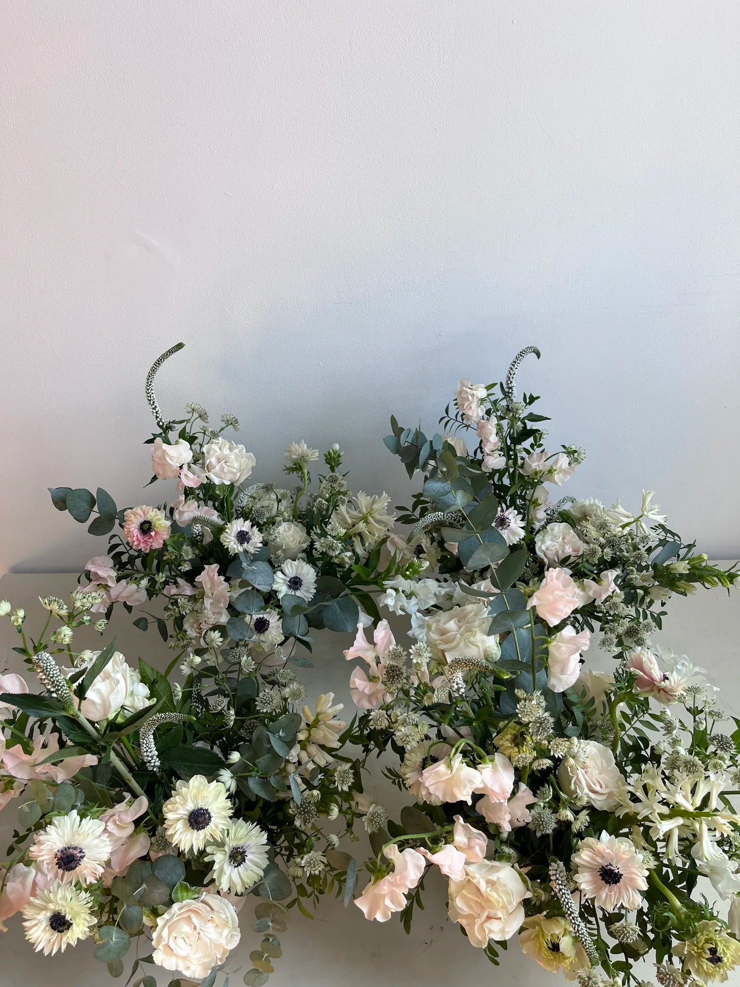 Floral arrangement with white, pink, and green flowers on a plain background