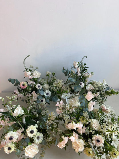 Floral arrangement with white, pink, and green flowers on a plain background