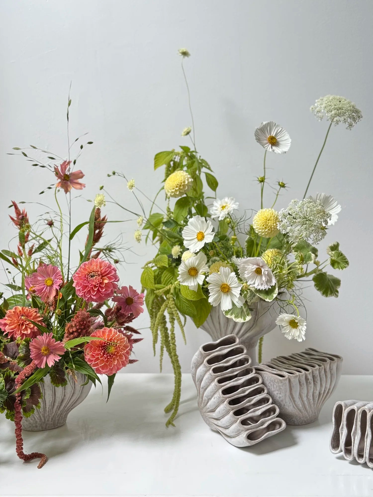 Ceramic vases with floral arrangements on a white surface