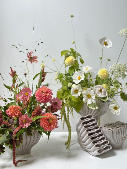 Four ceramic vases with floral arrangements on a light gray background
