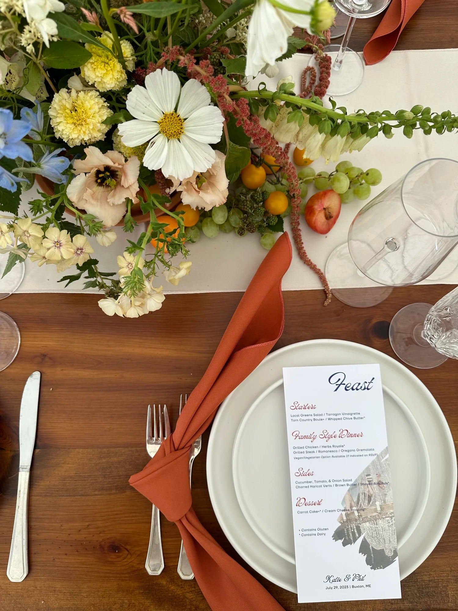 Elegant table setting with flowers, cutlery, and a menu card on a wooden table.