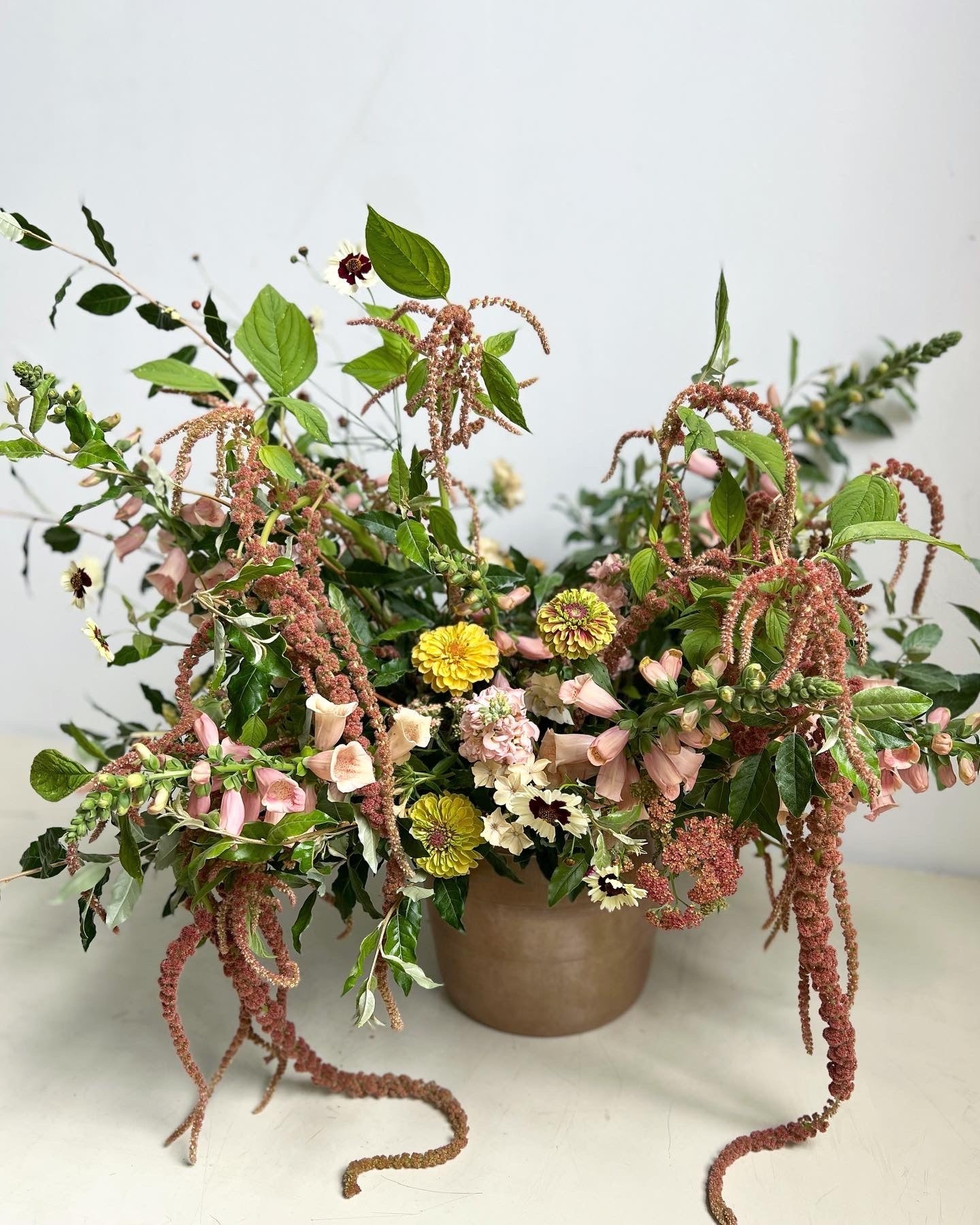 Floral arrangement with greenery and decorative elements on a white surface