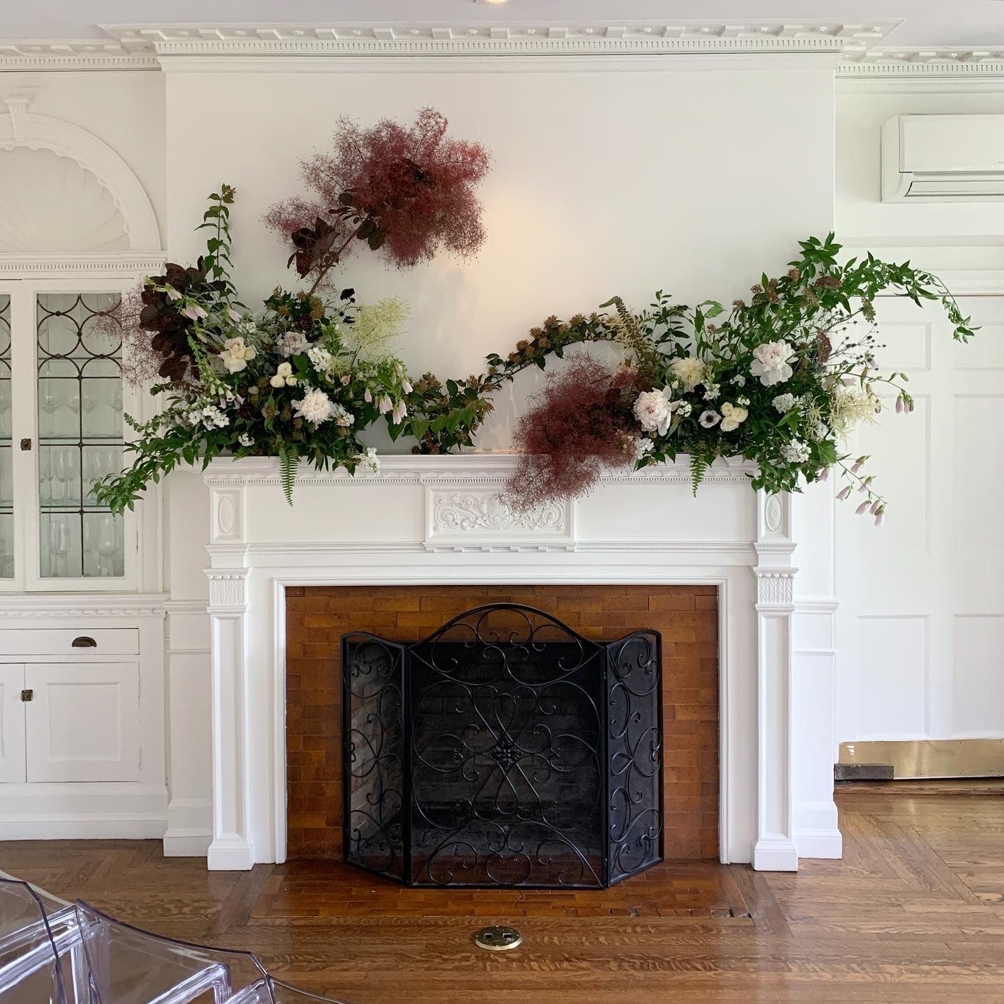 Floral arrangement on a white fireplace mantel with a decorative screen.