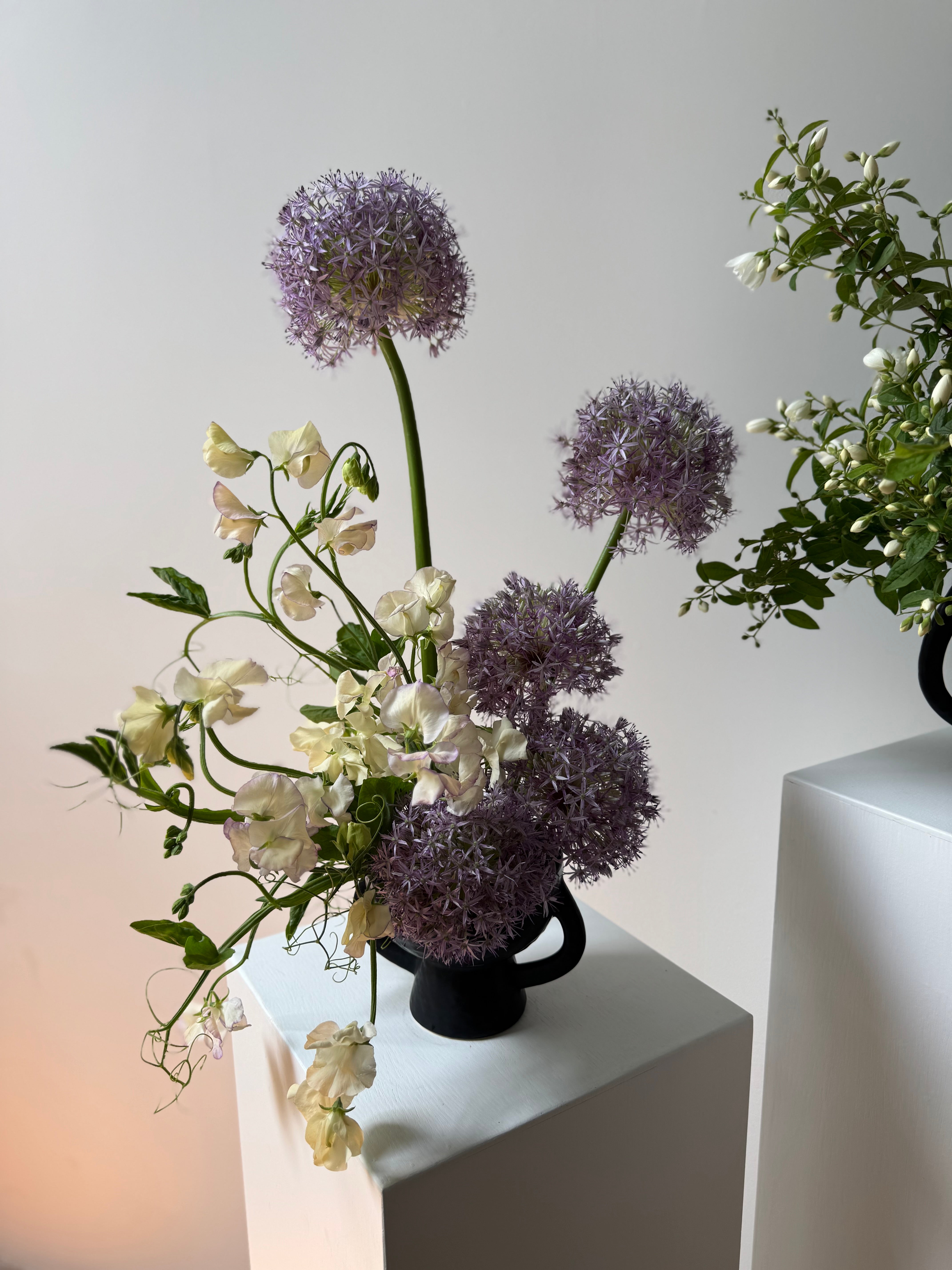 Beautiful Floral arrangement by portland maine florist with purple and white flowers in a black vase for sympathy