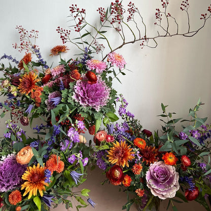 Colorful floral wreath with various flowers and greenery on a plain background