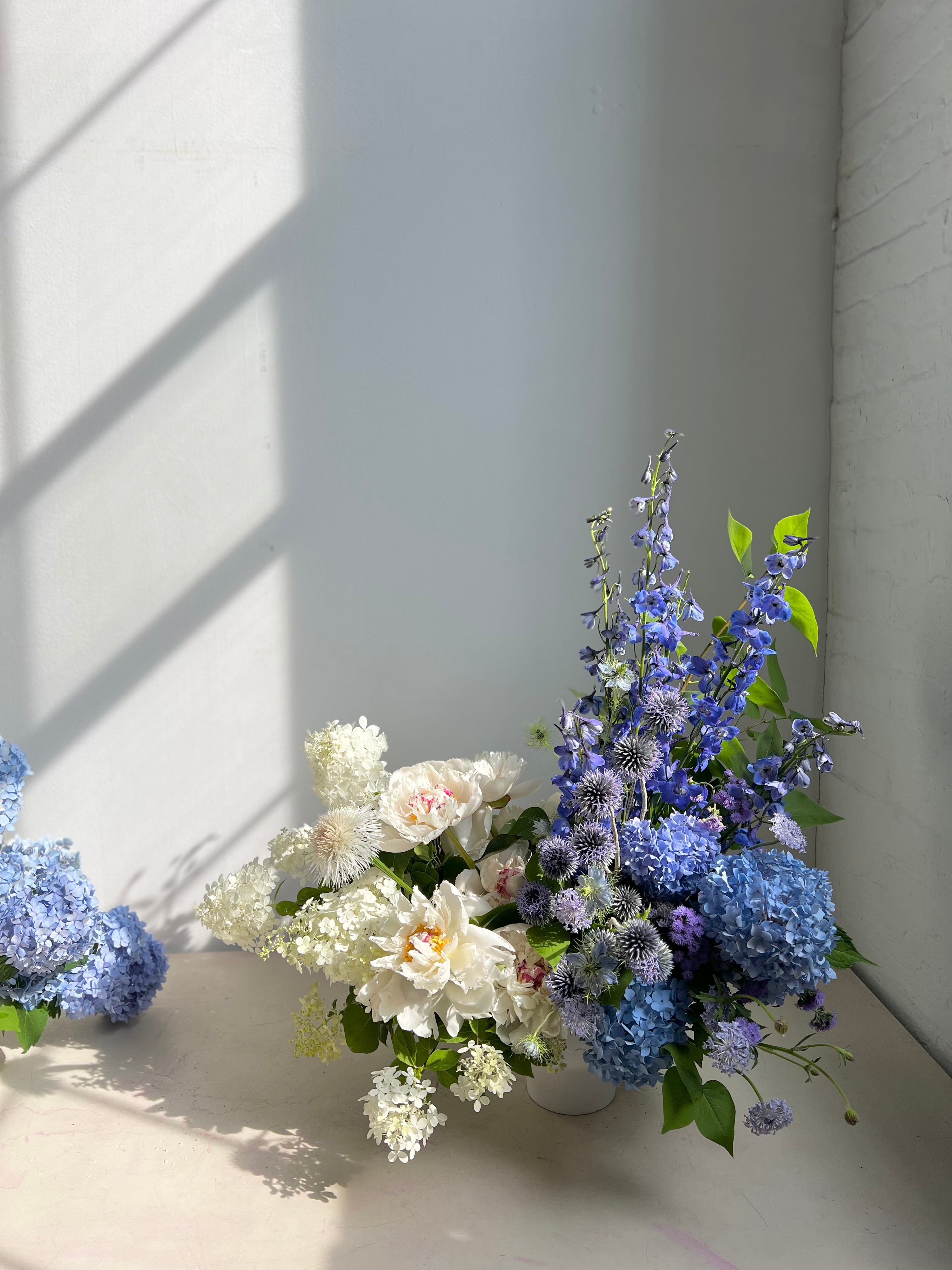 portland maine florist arrangement of blue and white sympathy flowers including peonies and delphinium