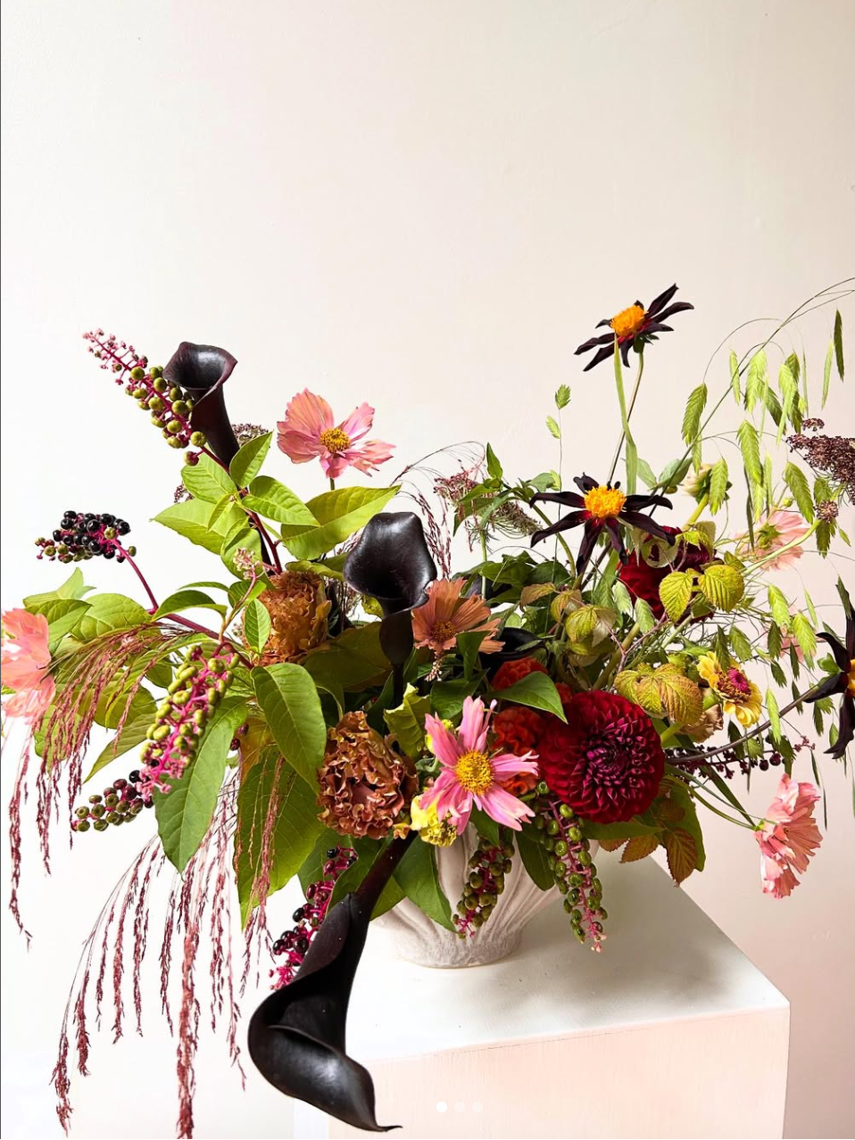Colorful floral arrangement in a vase on a white surface with a light pink background