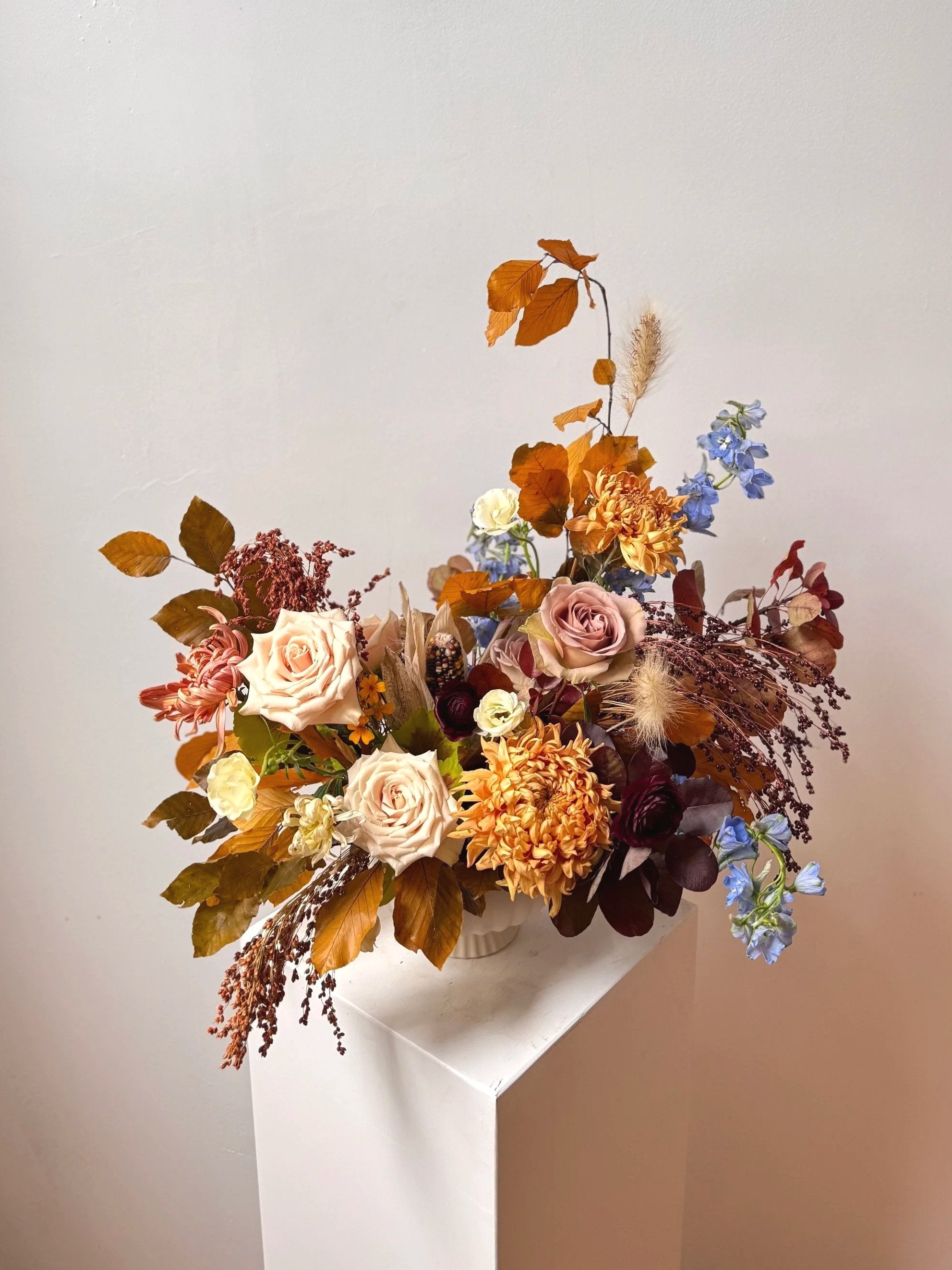 Autumnal flower arrangement with a white vase on a gradient background