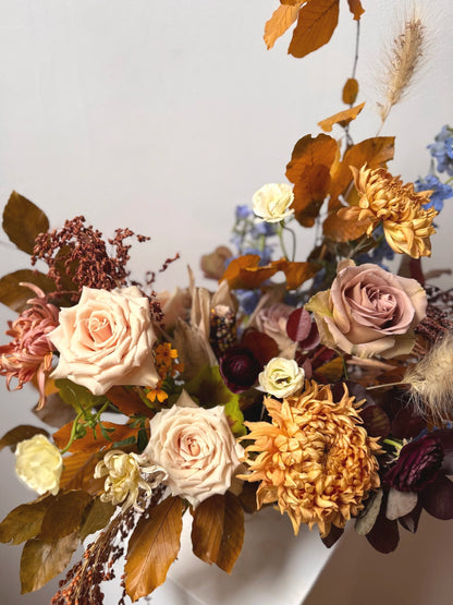 Autumnal floral arrangement with roses and dried leaves on a neutral background