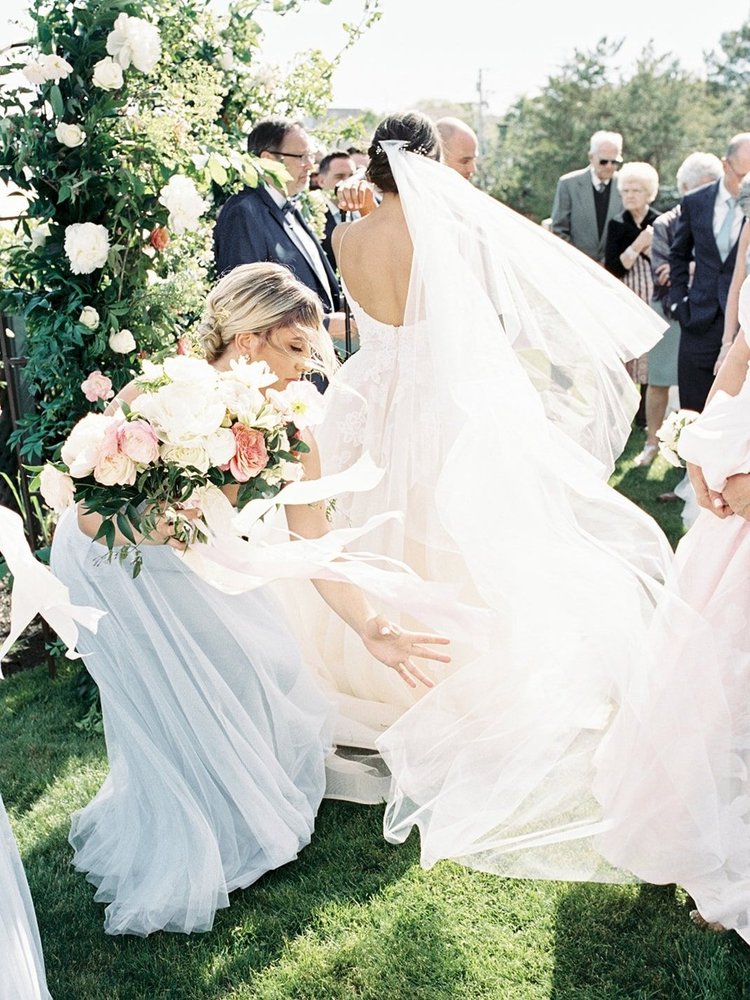 Bride and groom on a wedding day with floral decorations and guests in the background.