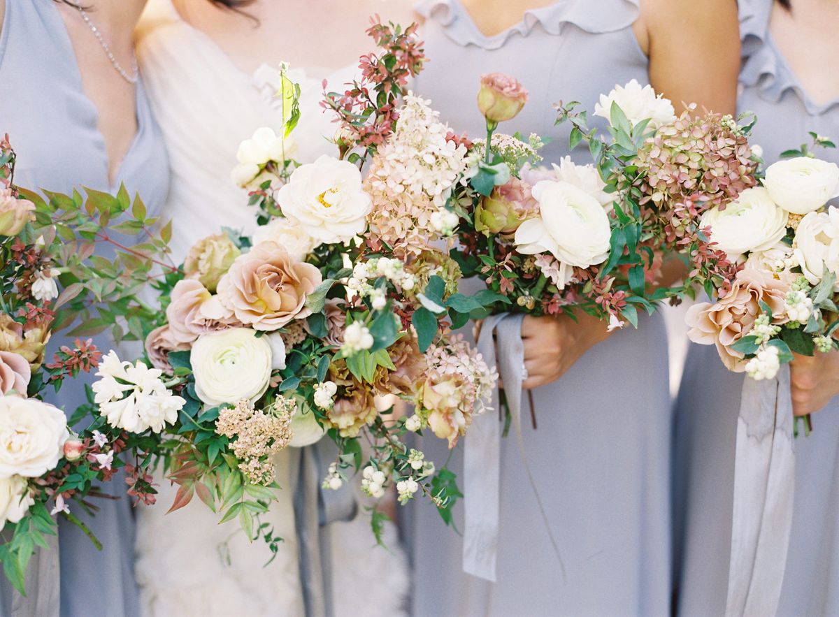 Bridesmaids in light blue dresses holding neutral floral bouquets with hydrangea.
