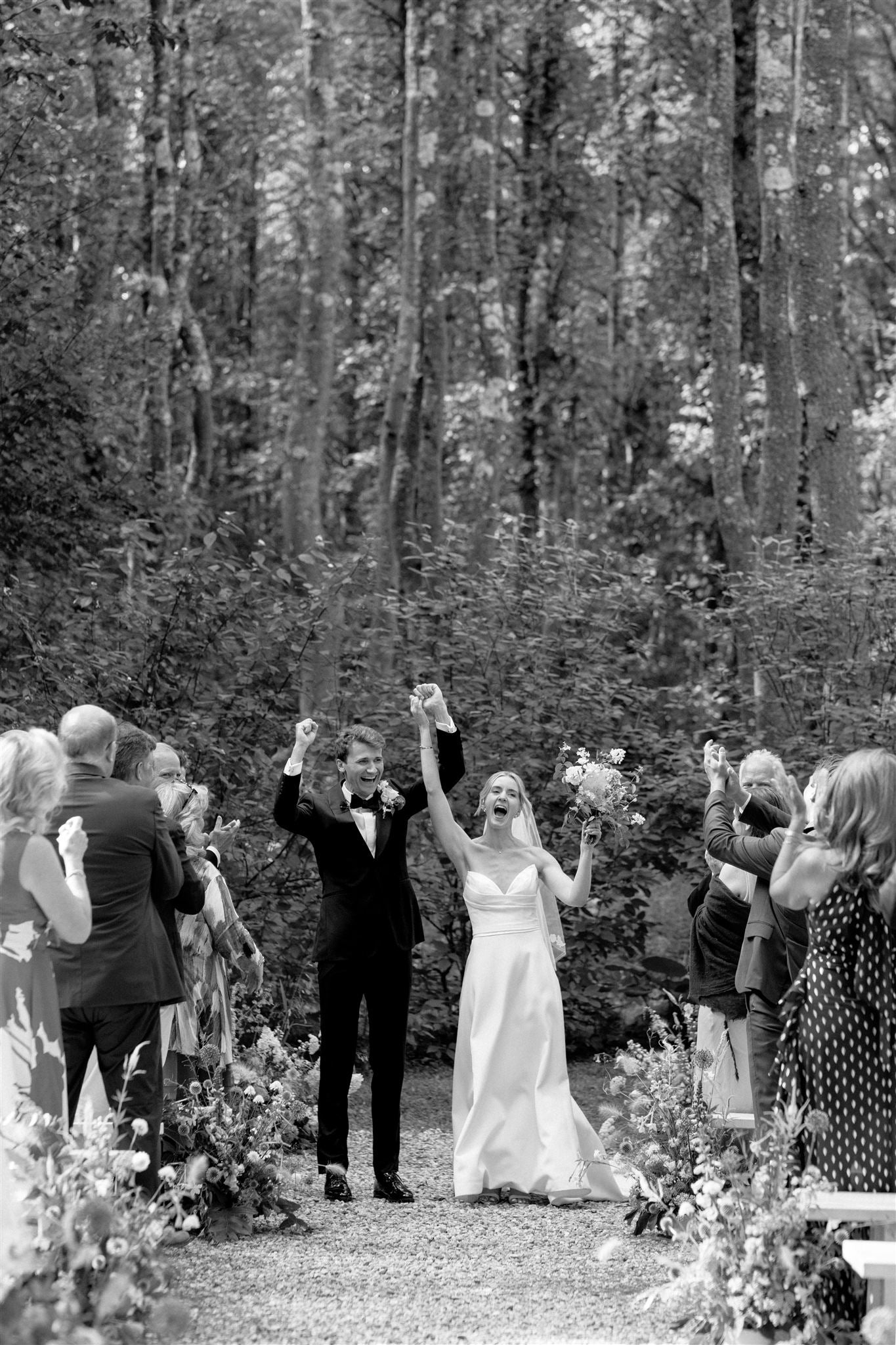 Wedding couple celebrating outdoors with guests in a forest setting