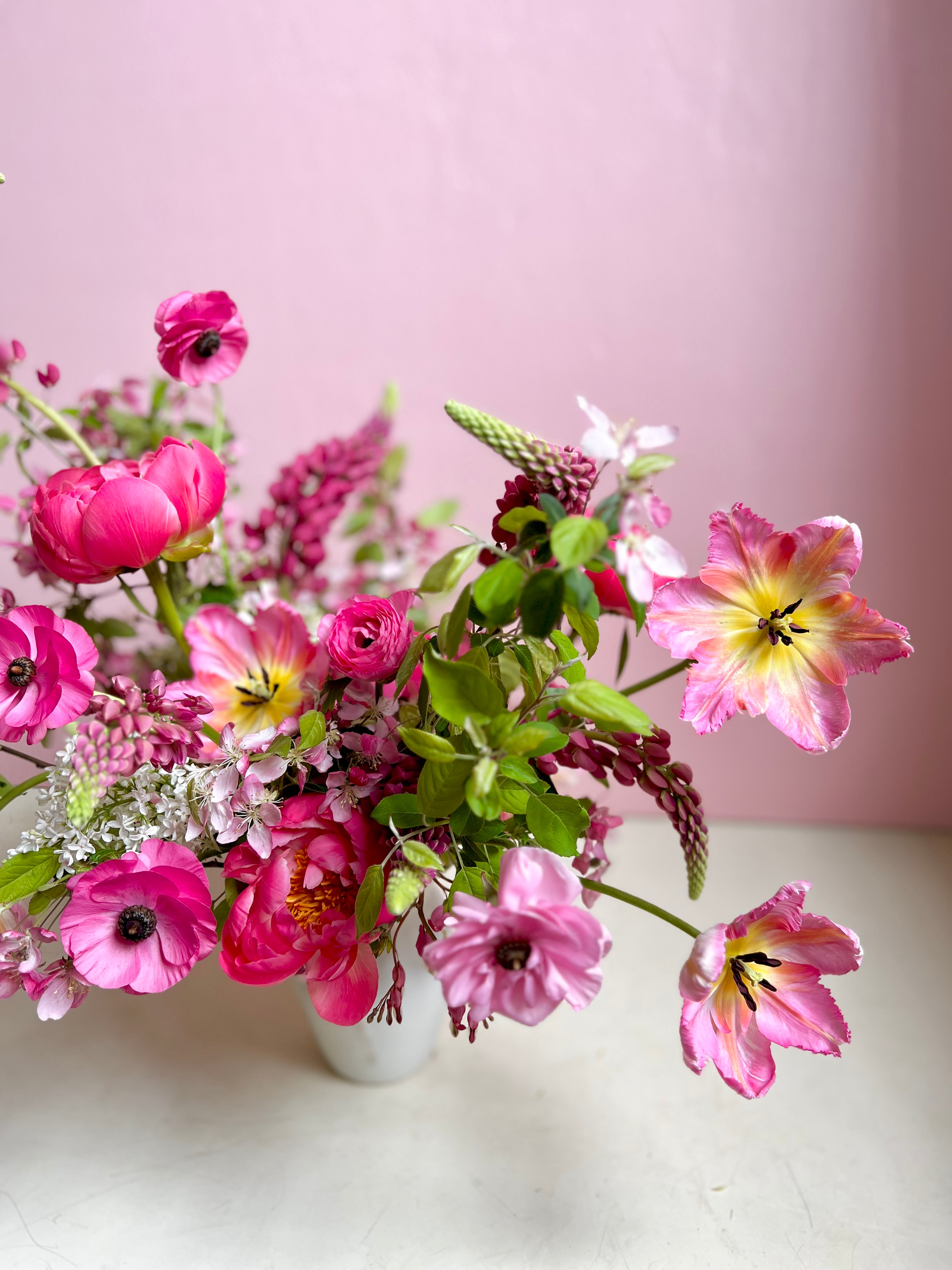 Bouquet of pink and yellow flowers in a white vase on a light pink background. from a portland miane florist for delivery